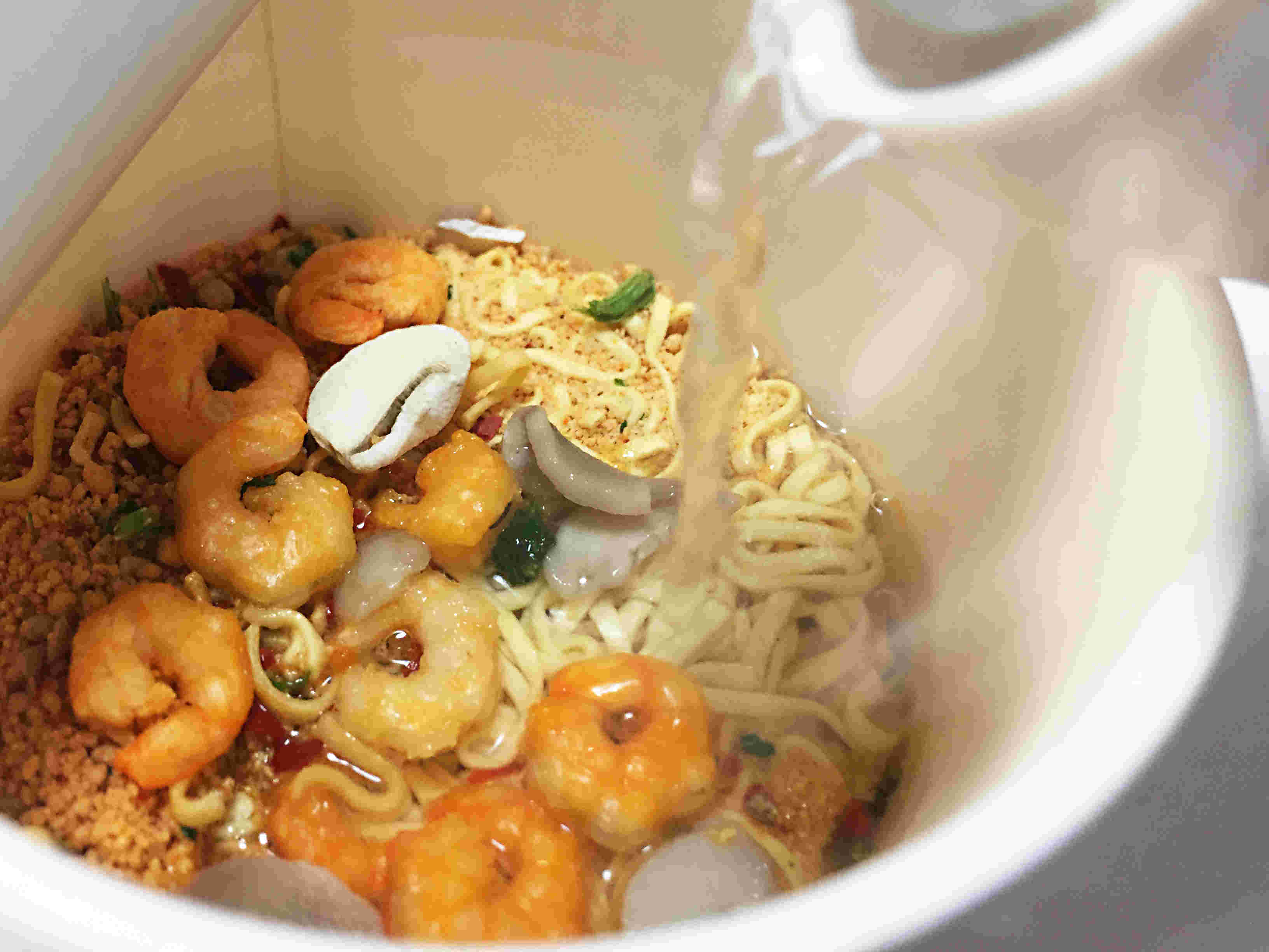 お湯を注がれるカップラーメン