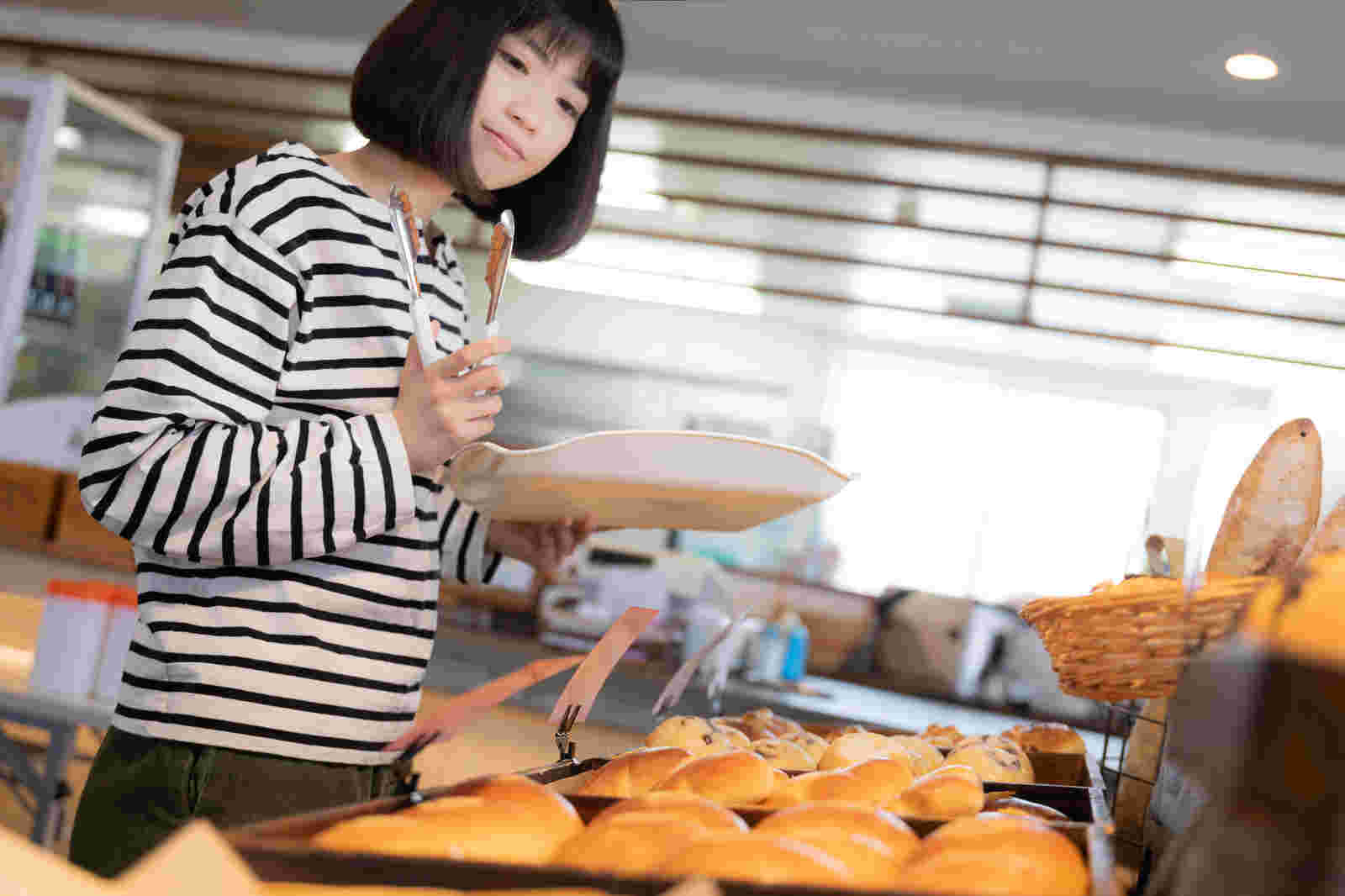 女性がお店でパン選びを楽しんでいる風景