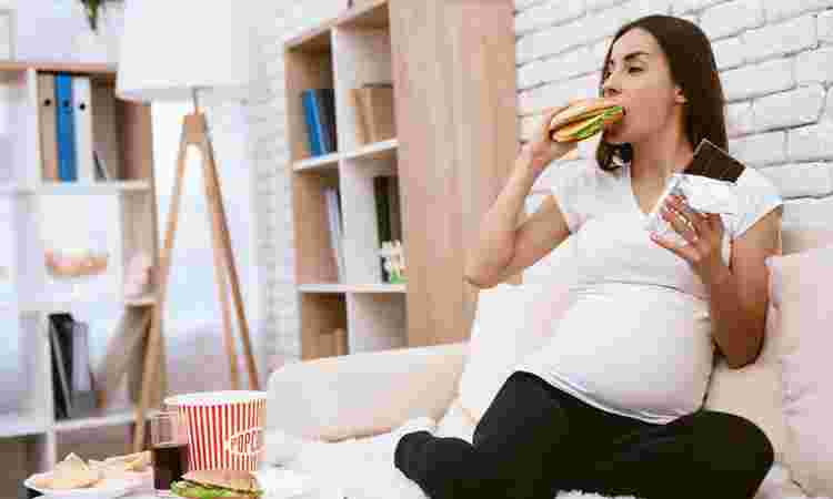 妊婦さんがハンバーガーとチョコレートを食べている様子