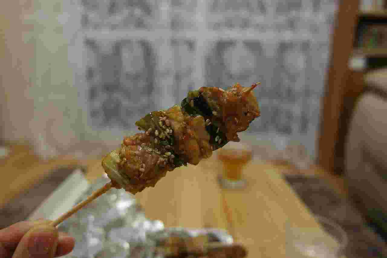 部屋を背景にビールとタレの焼き鳥が1本
