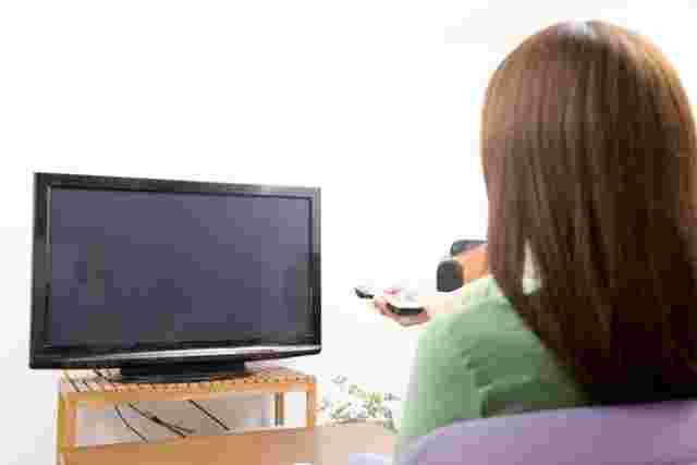 液晶テレビをつけようとする女性