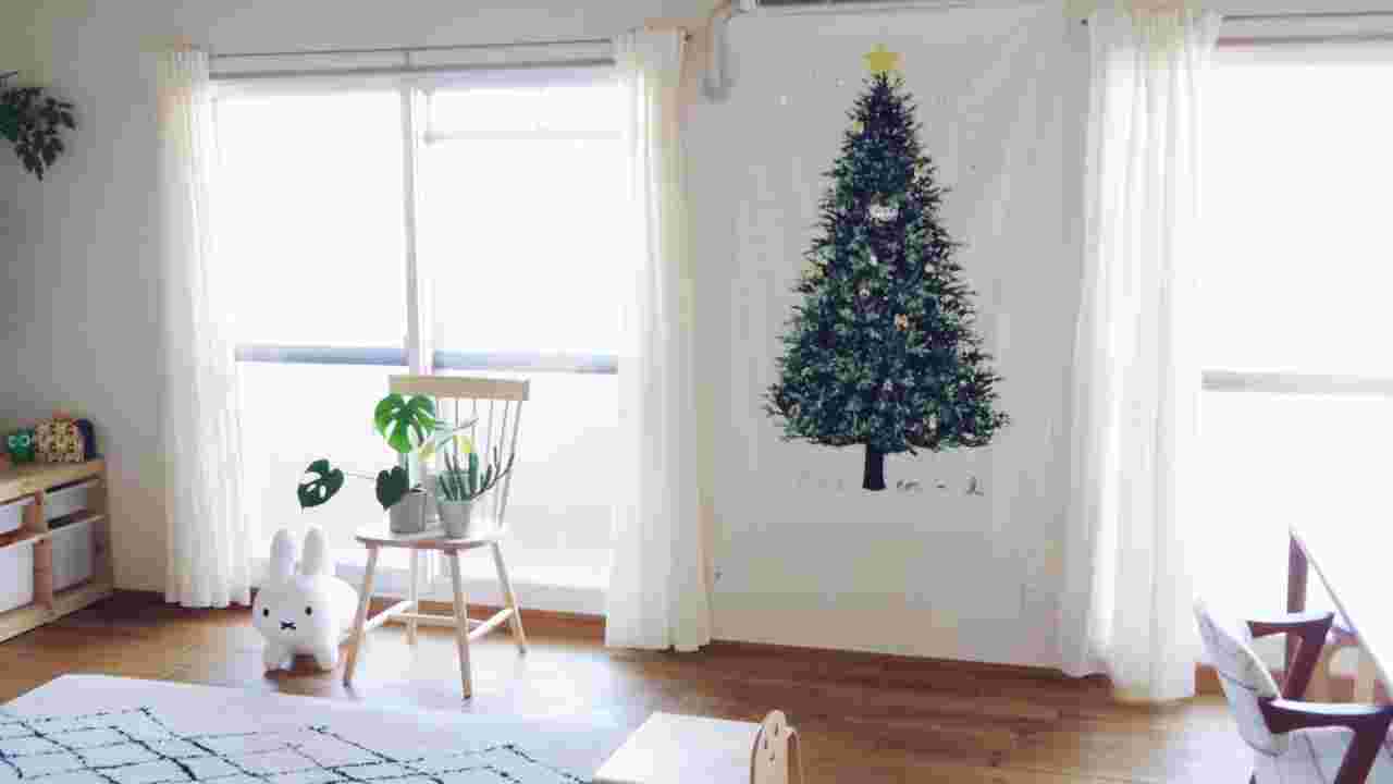 白を基調としたナチュラルテイストの部屋にクリスマスツリーのタペストリーが飾られている様子
