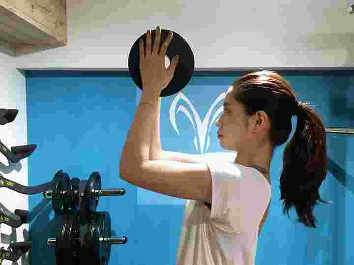 女性が器具を使って二の腕の筋トレを行っている様子