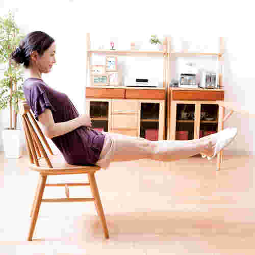 椅子を使って足上げ腹筋する女性