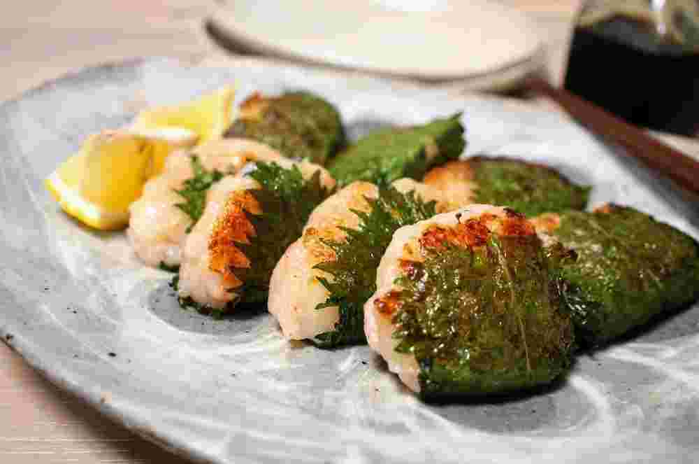 レモンが添えられた8つのエビしんじょうの大葉包み焼き
