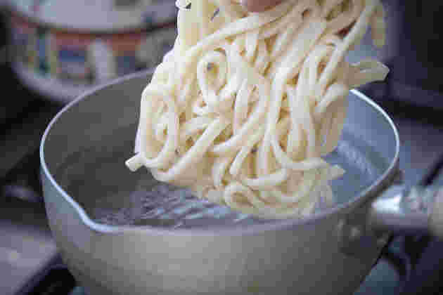 冷凍うどんを沸騰した鍋の中に入れようとしている様子