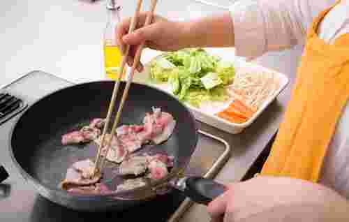 豚肉をフライパンで炒めている
