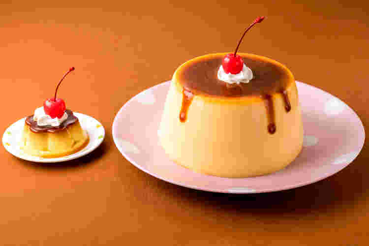 さくらんぼと生クリームが乗ったバケツプリンと普通サイズのプリンが並んでいる様子
