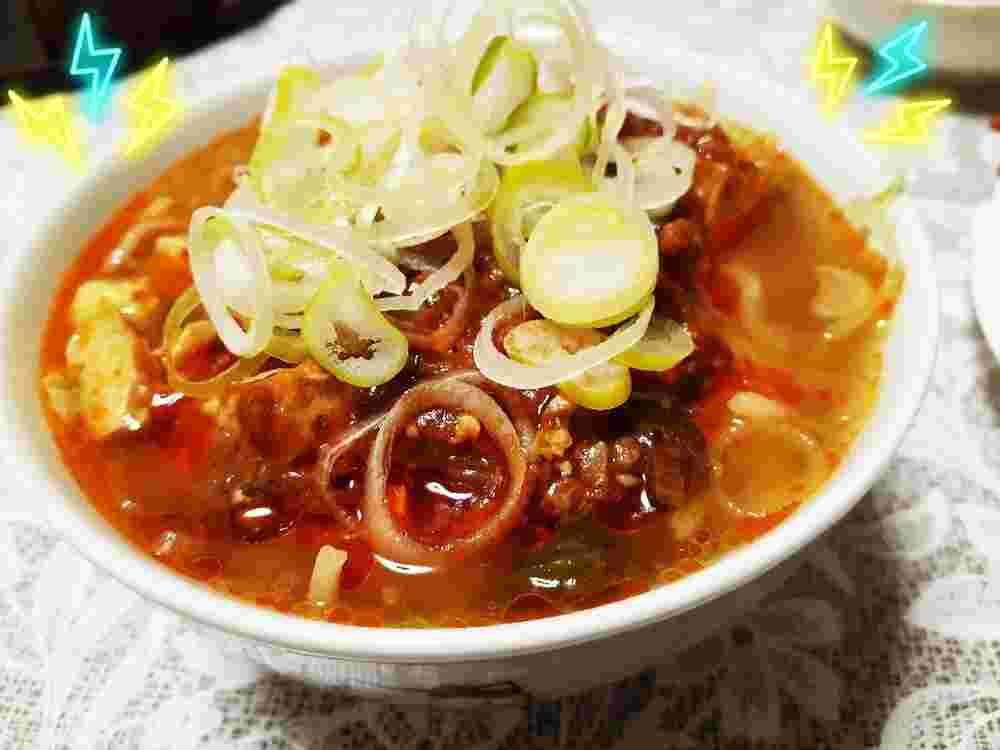 白いどんぶりに入ったたくさんのネギと麻婆豆腐のラーメン
