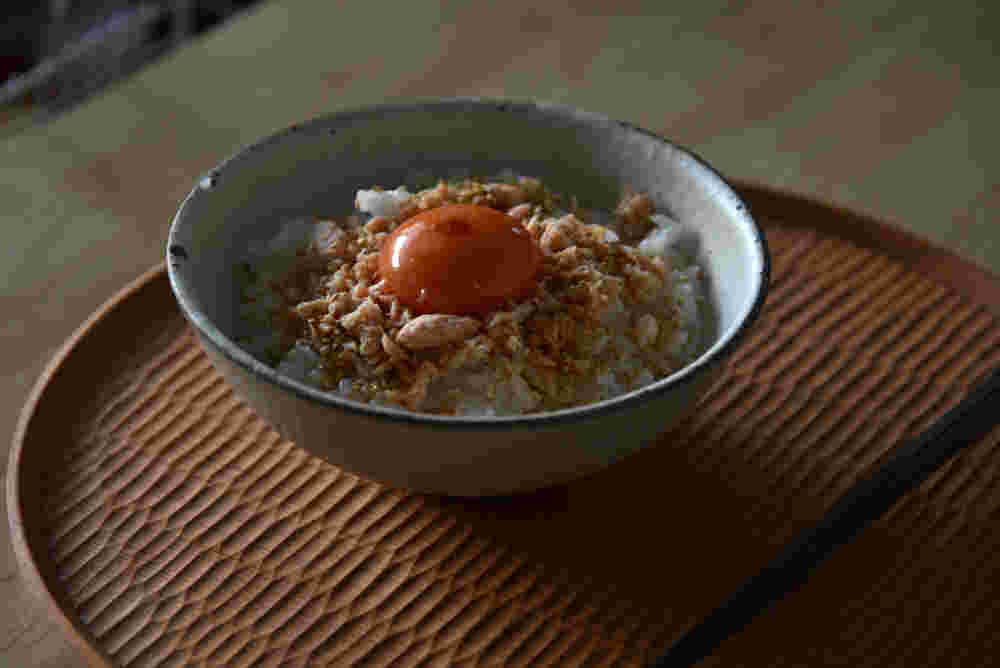 お茶碗にご飯と鮭フレークと卵黄が盛られている様子