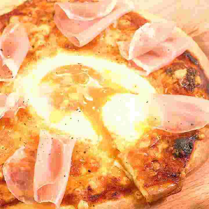 生ハムや卵が乗ったピザ