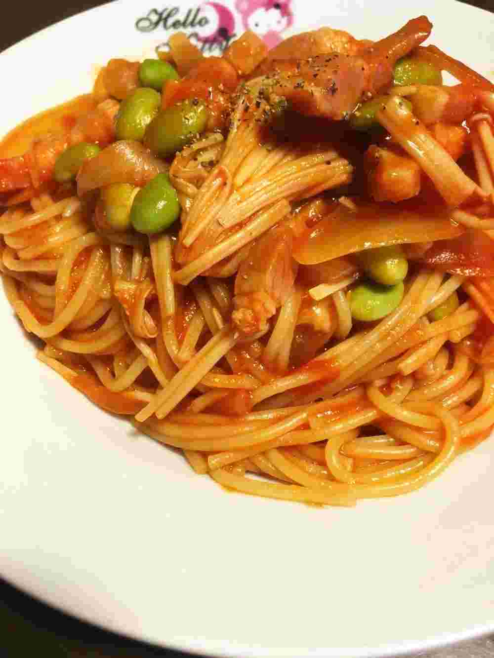 白い器に盛られたベーコンとえのきと枝豆のトマトスパゲティ