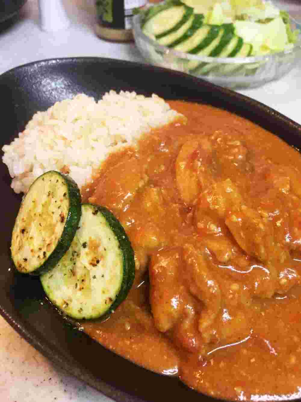 サラダと黒い皿に盛られたバターチキンカレー