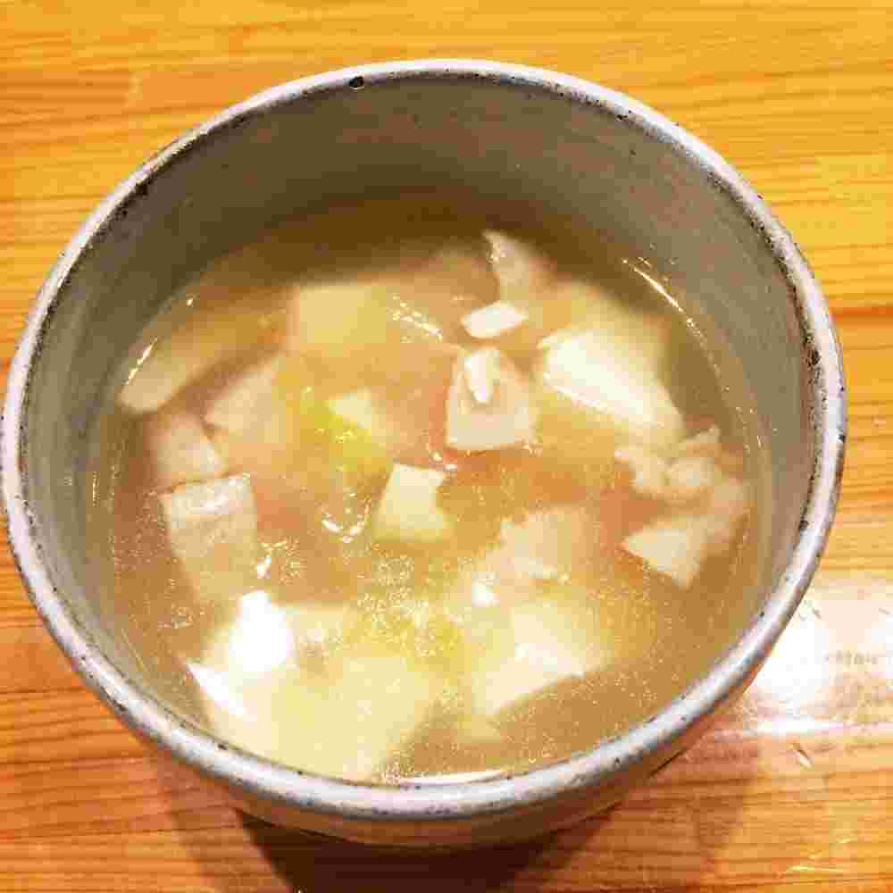 灰色に器に盛られている豆腐とベーコンのコンソメスープ