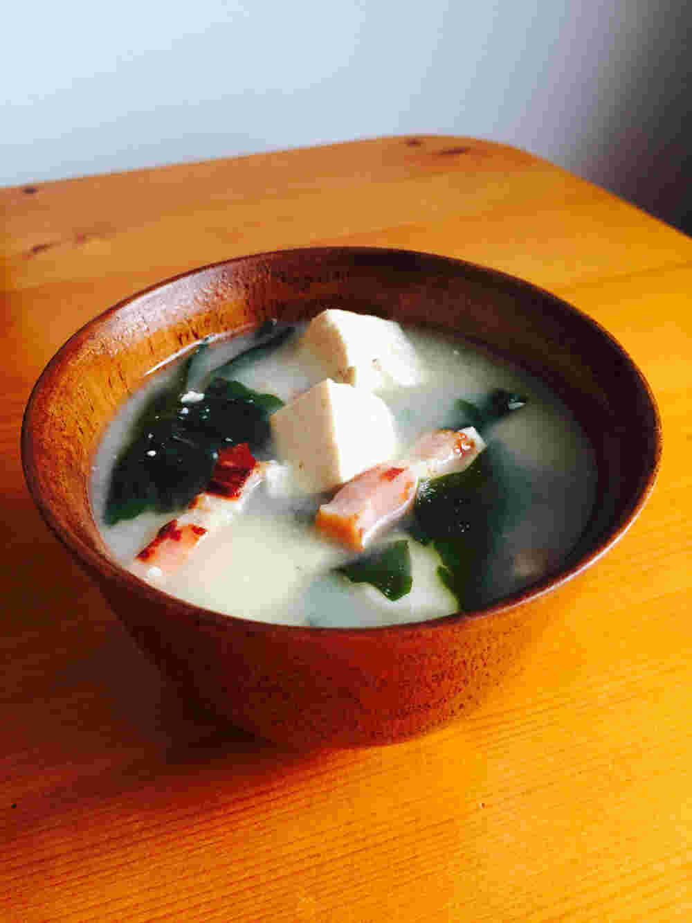 漆のお椀に入った木綿豆腐とベーコンの味噌汁