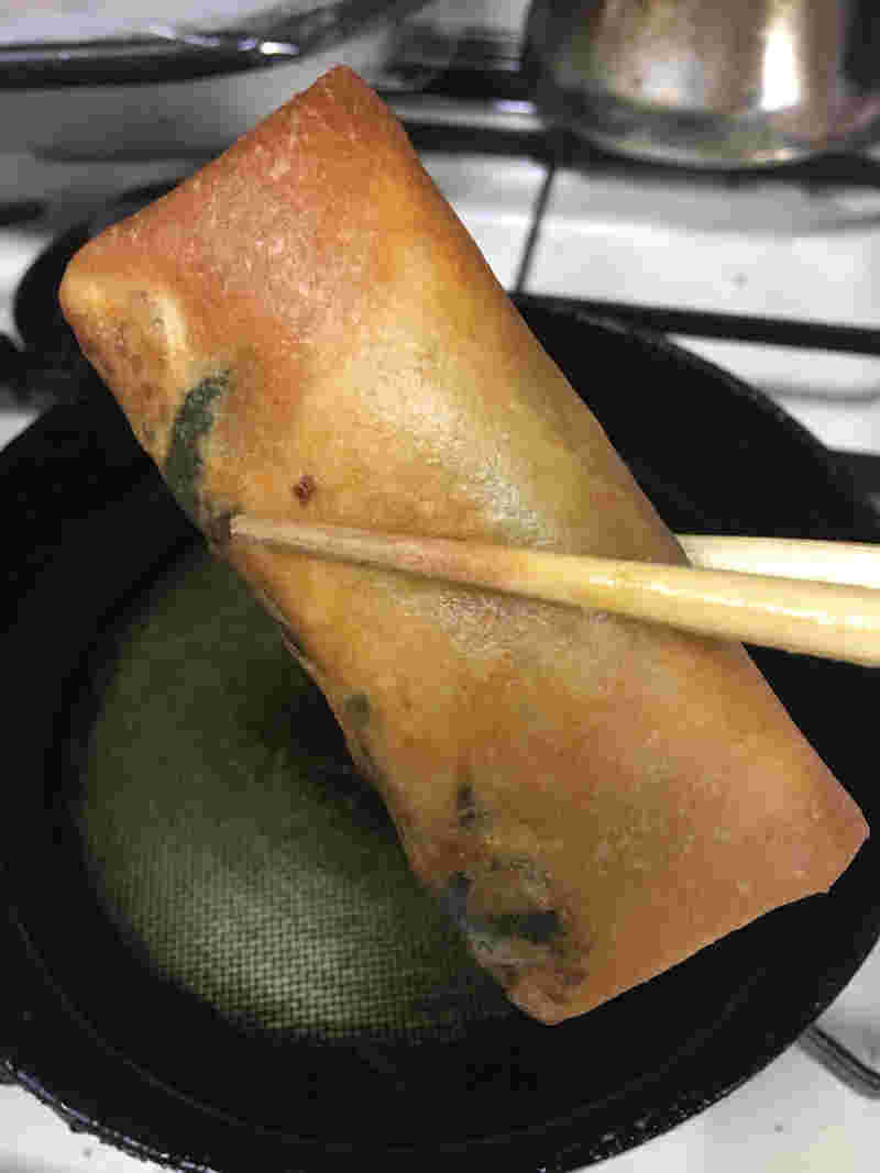 フライパンでひき肉入りの春巻きを揚げている様子