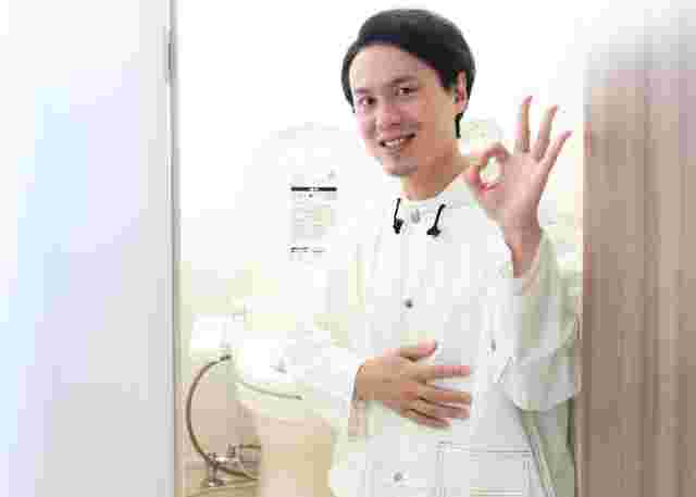 トイレの前でOKサインを出す男性