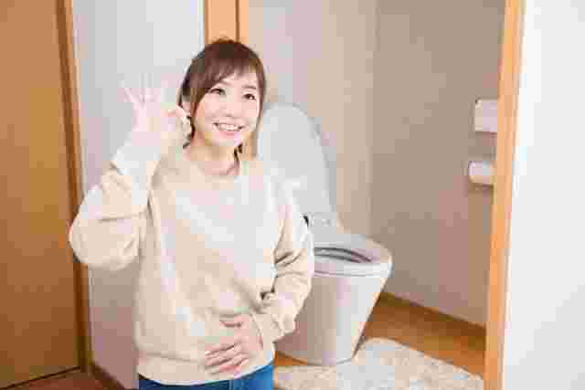 トイレの前でOKサインをする女性