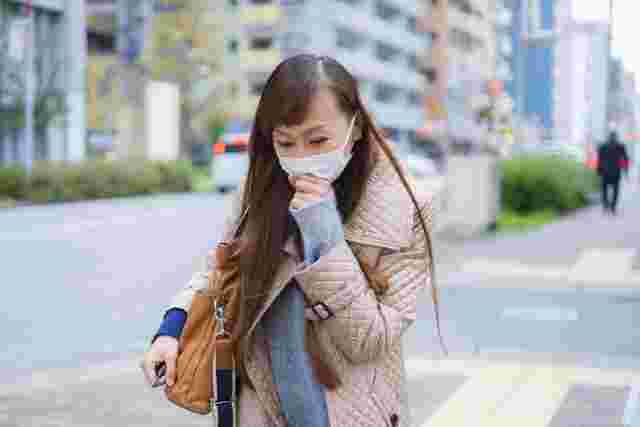 マスクの上から咳をする女性