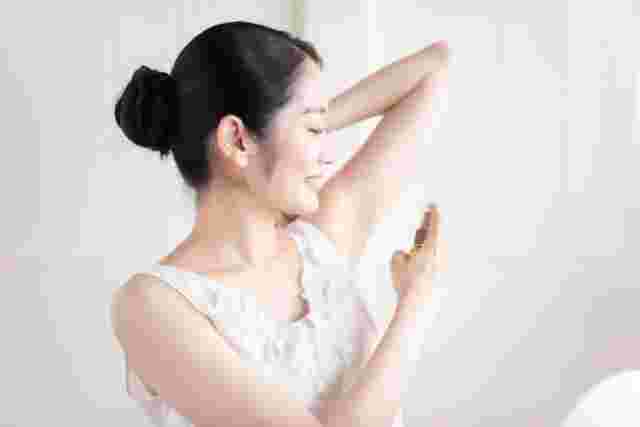 脇に制汗スプレーをかける女性