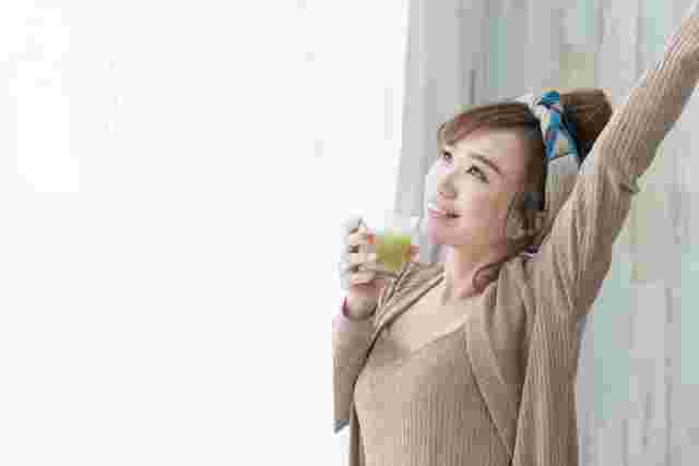 ドリンクを片手に伸びをする女性