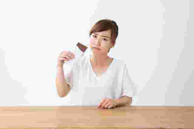 チョコレートを食べて顔をしかめる女性