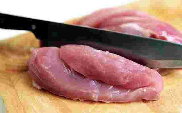 生の鶏肉をカットしている包丁