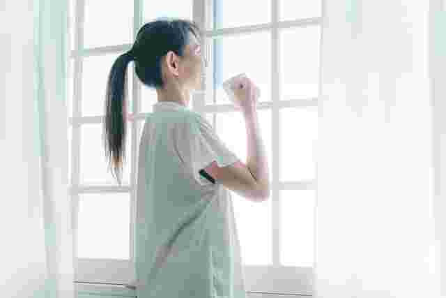 窓を見ながら養命酒を飲む女性