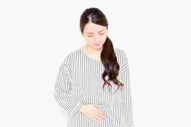 体調が悪くお腹を押さえている女性