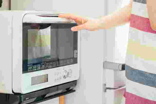 電子レンジを開けようとする女性